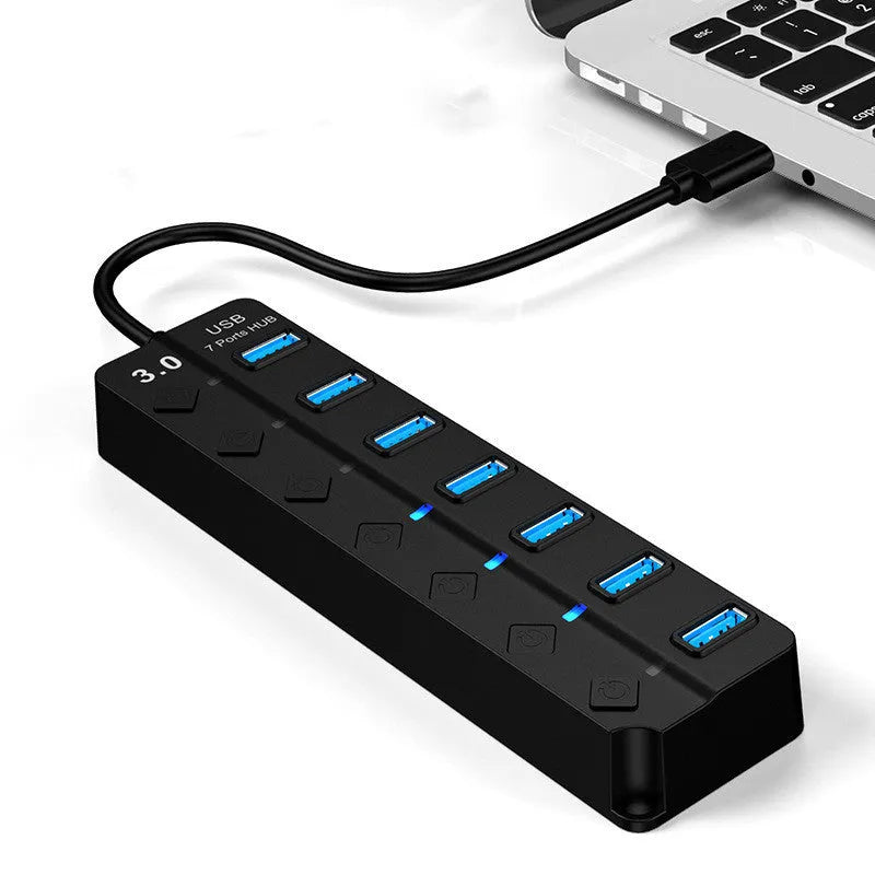 Black 7-port USB 3.0 hub with external power adapter and cable on a desk