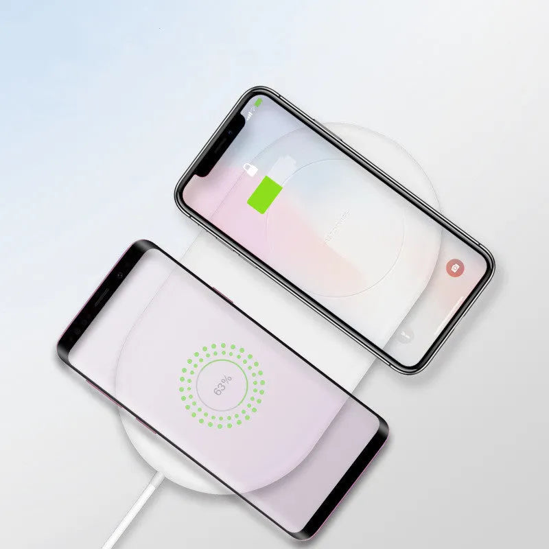 Simple white wireless charging pad showing two mobile phones charging simultaneously on its surface.