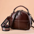 Round leather handbag in wine red with a soft handle and zipper closure.