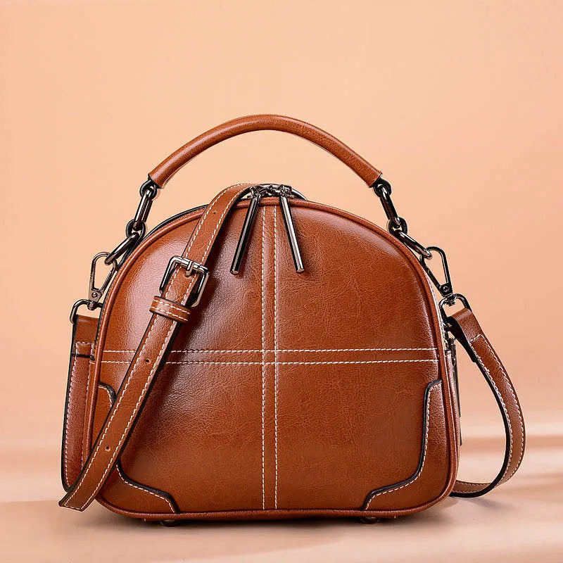 Round leather handbag with a zip closure and soft handle in a choice of colours.