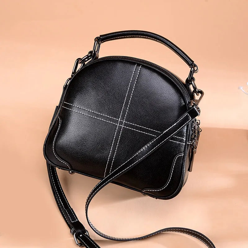 Round leather handbag with a zip closure and soft handle in a choice of colours.