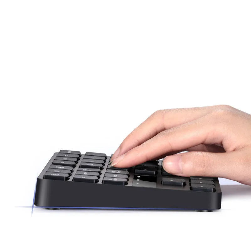 Black wireless numeric keyboard with 35 keys on a desk next to a laptop