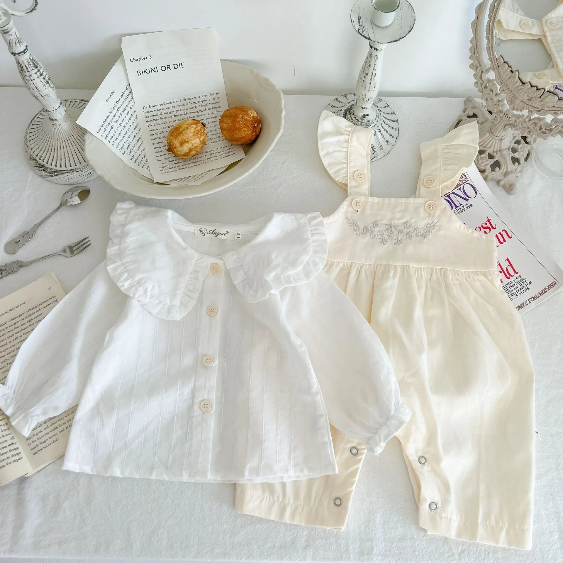 Baby girl wearing a loose-fit cotton suspender romper with adjustable straps in an apricot colour.