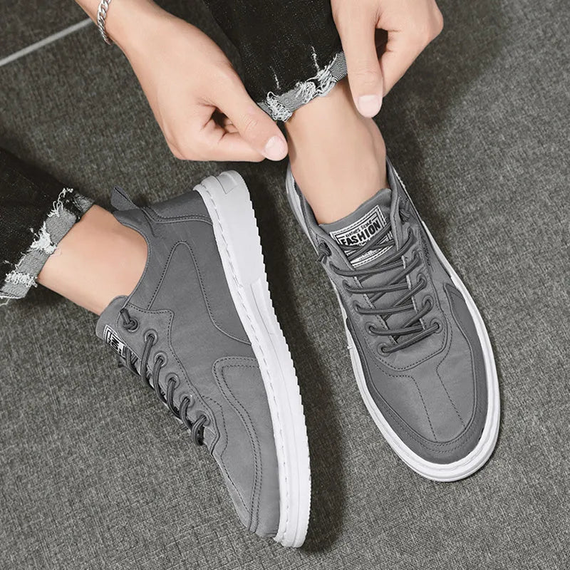 Men's green canvas lace-up sneakers with round toe, flat heel, and letter print side detail on a white background