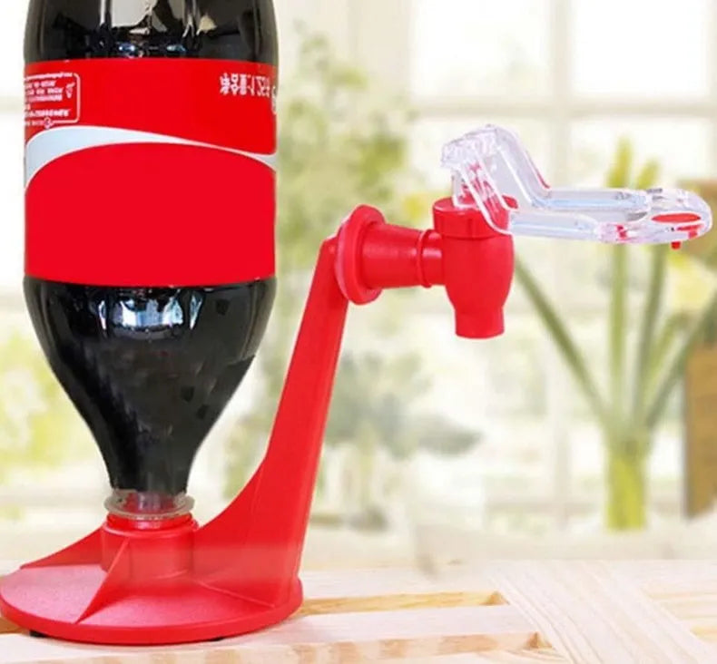 Red Magic Tap plastic soda dispenser attached to an inverted 2-litre bottle on a table.