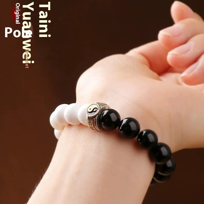 Black and white obsidian Tai Chi bracelet with geometric beads showing mantra inscriptions.