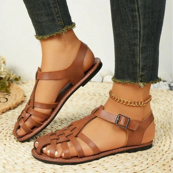 Dark brown women's Roman sandals with woven PU upper and buckle closure on a rubber sole.