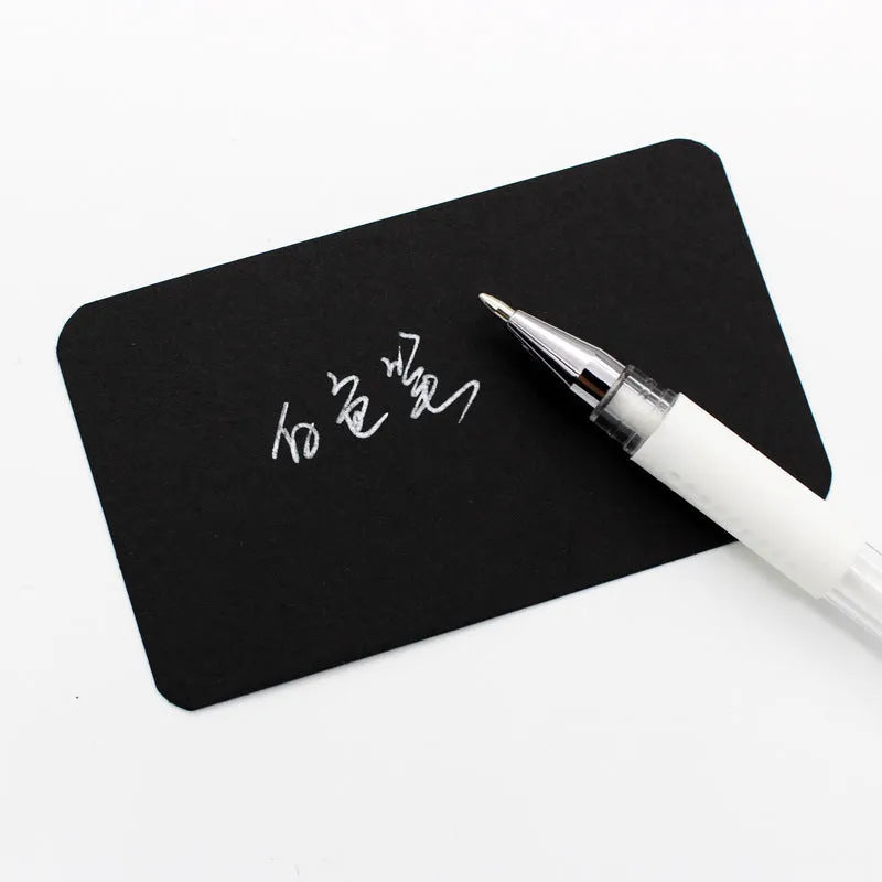 White hard pen calligraphy pen with cap closure on a dark surface showing white ink lines