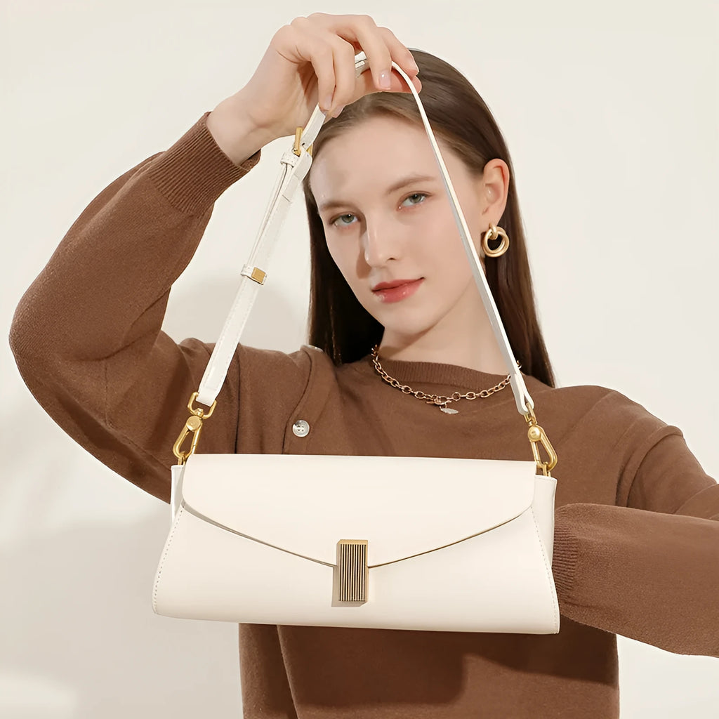 Cowhide leather cross-body shoulder bag in pillow shape with clamshell opening showing internal phone and document pockets