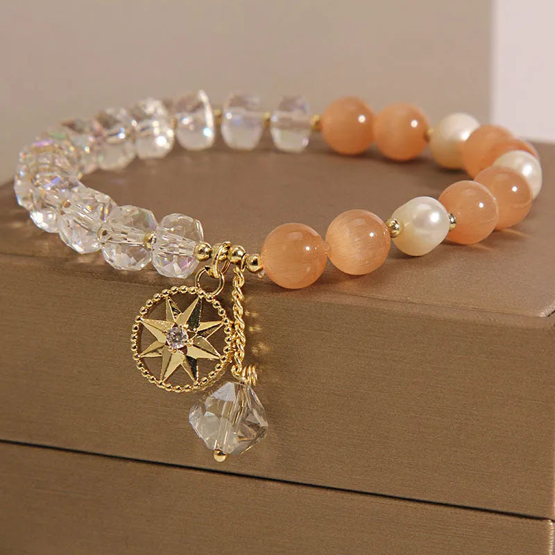 Gold-plated women's bracelet with an eight Awn star charm holding an inlaid orange opal crystal.