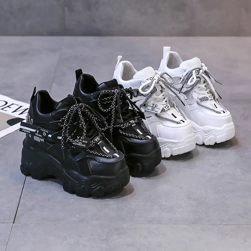 White women's low-top platform sports trainers with mesh panels and a black cross-strap on a rubber sole.