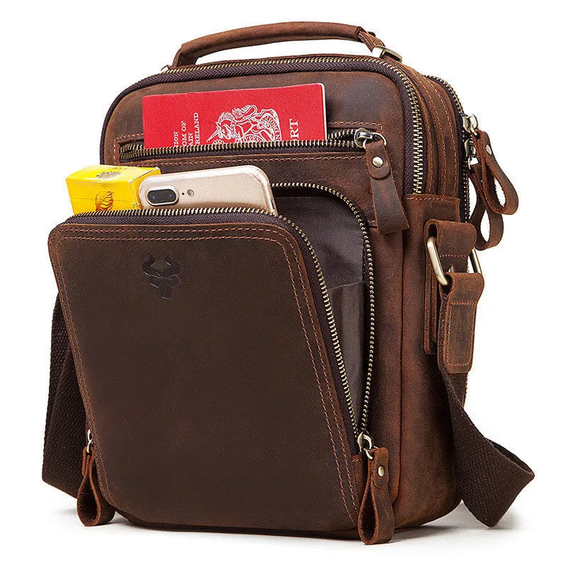 Men's brown Crazy Horse leather crossbody bag with sewing line detail on a table.