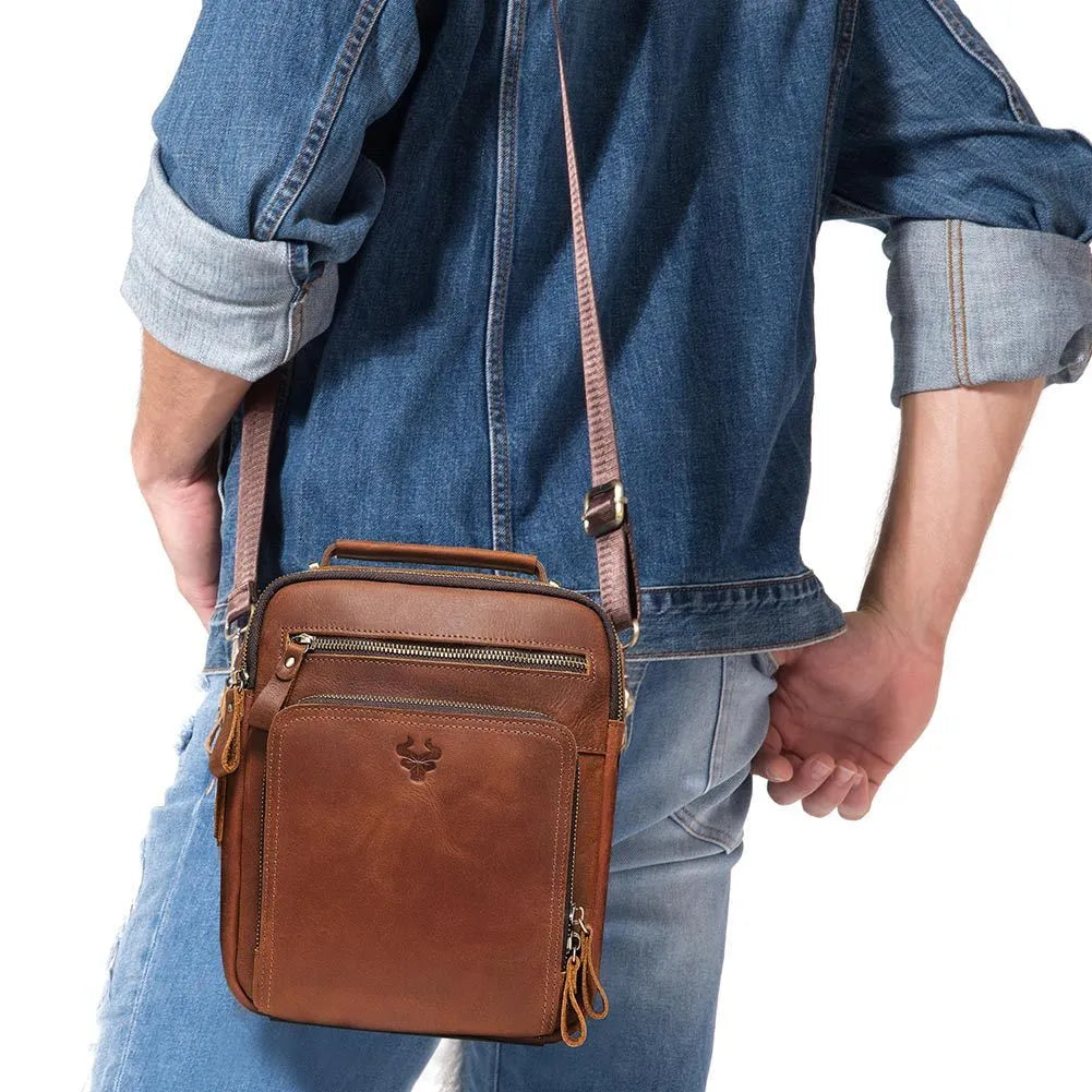 Men's brown Crazy Horse leather crossbody bag with sewing line detail on a table.
