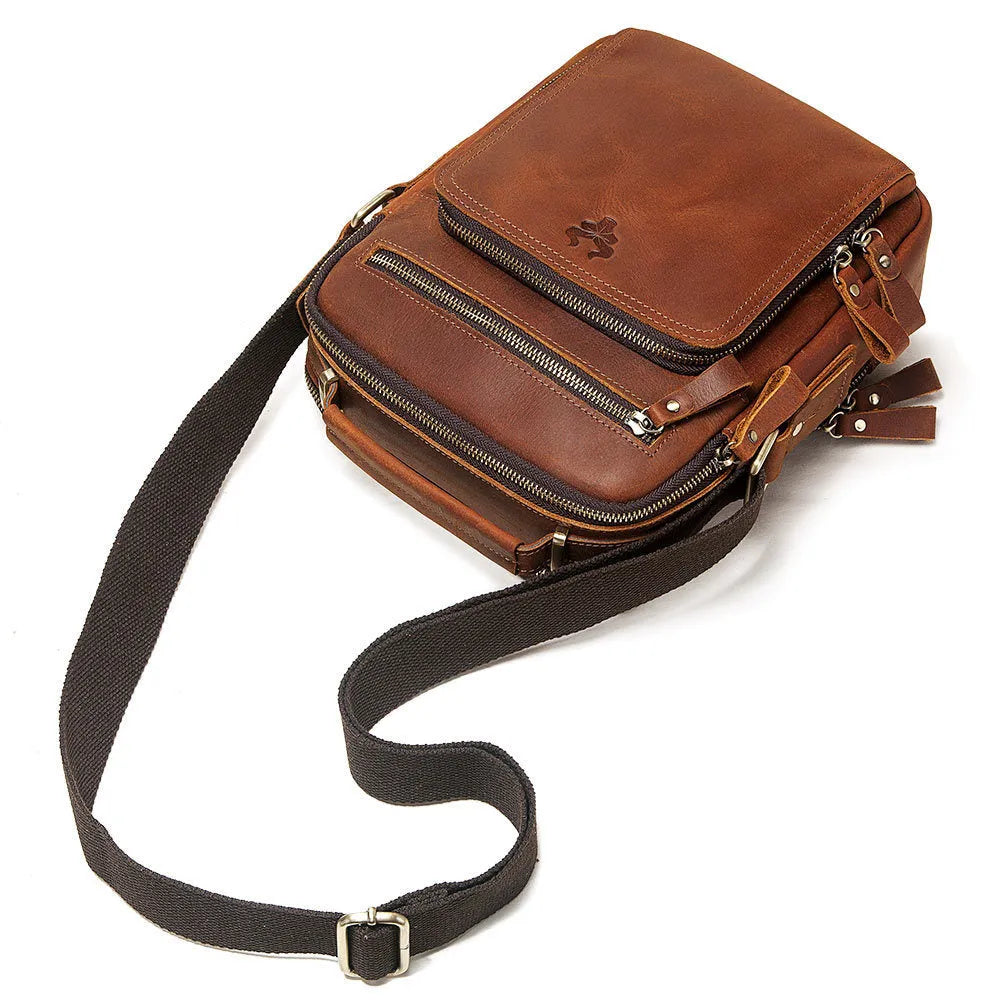 Men's brown Crazy Horse leather crossbody bag with sewing line detail on a table.