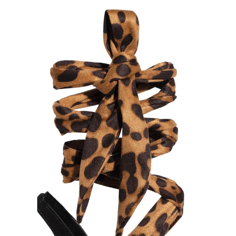 Light brown leopard print women's high heel sandals with cross-straps and a thin 8cm stiletto heel on a rubber sole.