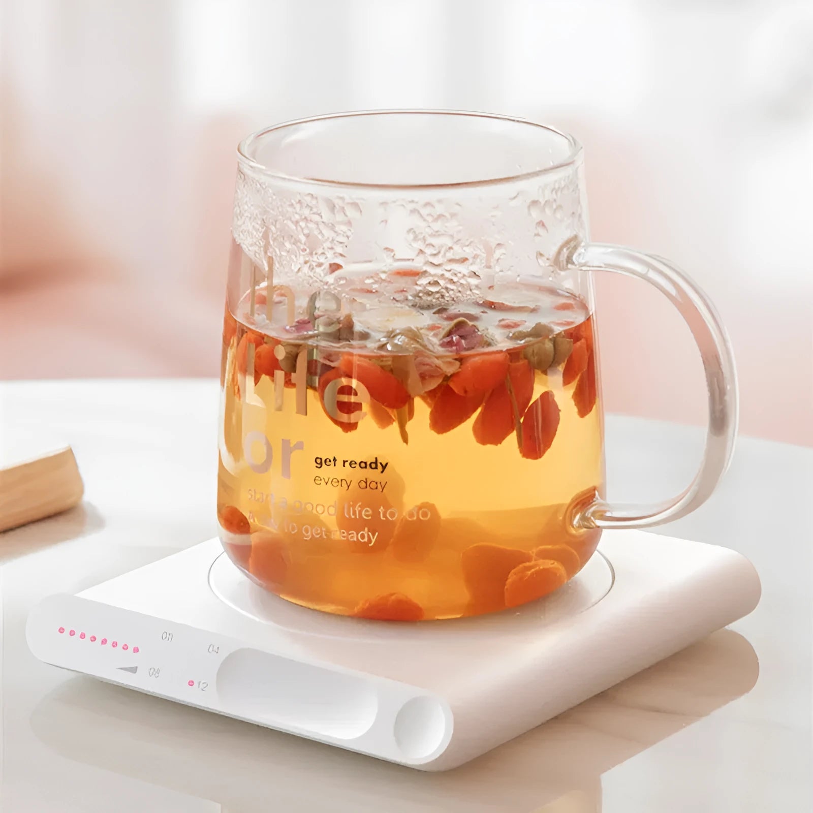Pink and white USB-powered heating cup pad with mechanical timer control for keeping mugs warm.