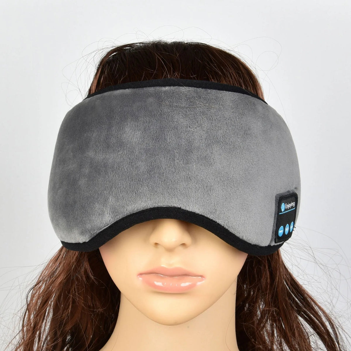 Soft satin sleep eye mask in black with adjustable strap lying flat on a light background