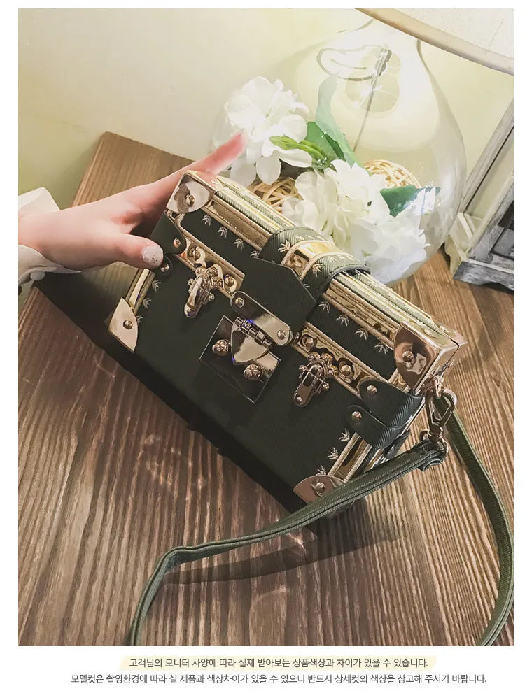 Hard-sided black women's shoulder bag with a flap closure, adjustable strap, and decorative metal rivets.