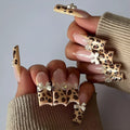 Leopard print pattern false nails with butterfly charms from a plastic nail art kit.