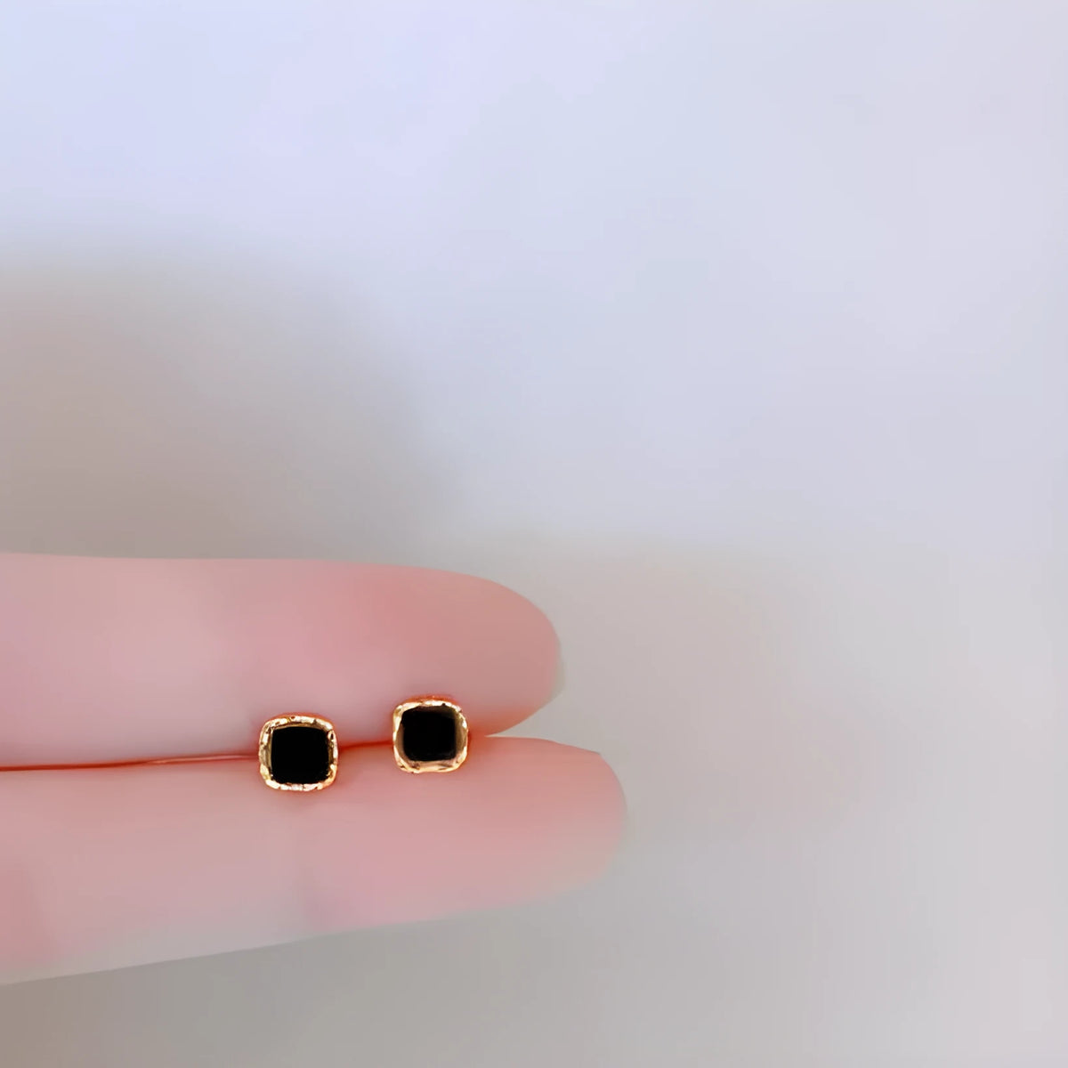 Black round mini ear studs with inlaid zircon, silver plated alloy, 10mm diameter, on a plain background