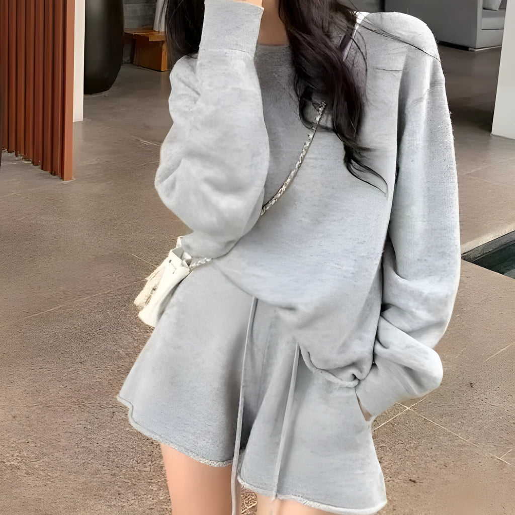 Woman wearing a loose grey knitted long-sleeve sweater and matching wide-leg shorts two-piece set.