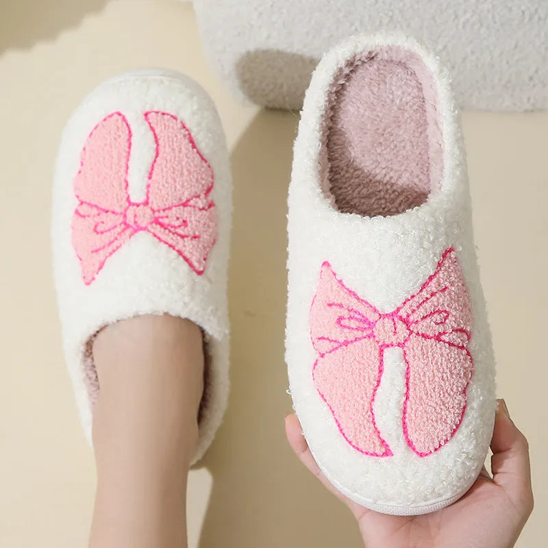 A pair of pink cartoon bow knot suede slippers with a TPR sole, shown from the side.
