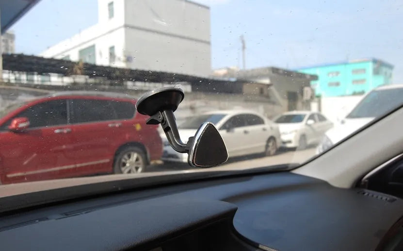 Classic black magnetic car phone holder mounted on a car dashboard, showing 360-degree rotation.
