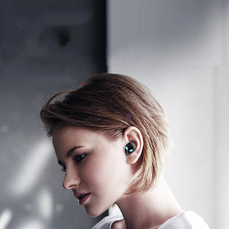 Creative Outer T8 Starman alien design Bluetooth earbuds with LED lights next to wireless charging case.