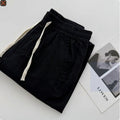 Man wearing beige loose-fit straight leg casual trousers with a drawstring waistband.