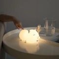 Dudu pig cartoon night light with silicone lampshade and warm yellow LED glow on a bedside table