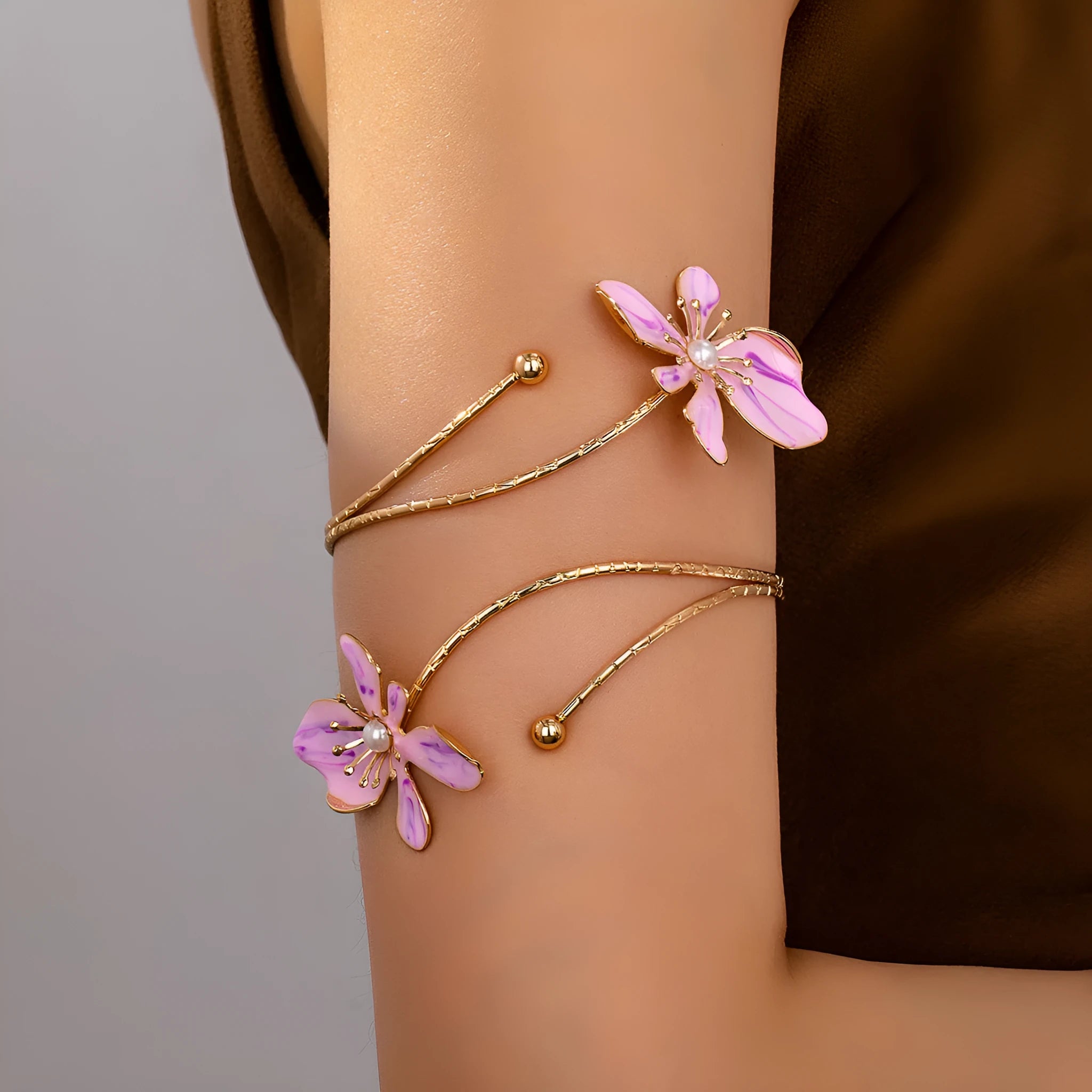 Close-up of a polished pink alloy armband with a hollow geometric pattern, shown on a wrist.