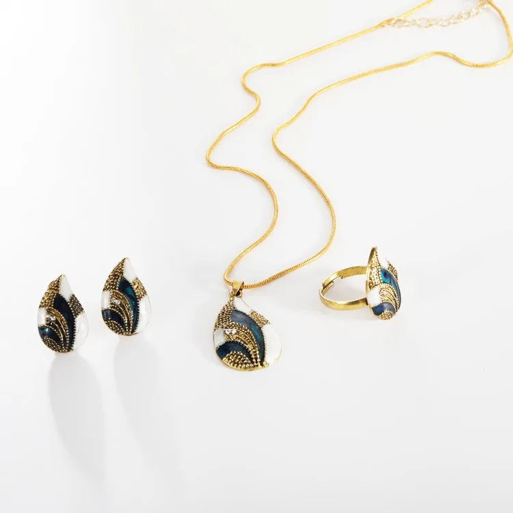 Gold water drop jewellery set with necklace, earrings, and ring on white background