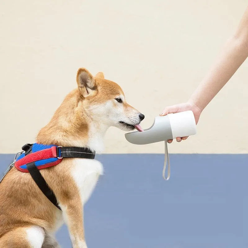 Moestar rocket-shaped pet drinking cup in white with grey or orange accents showing one-button lock mechanism