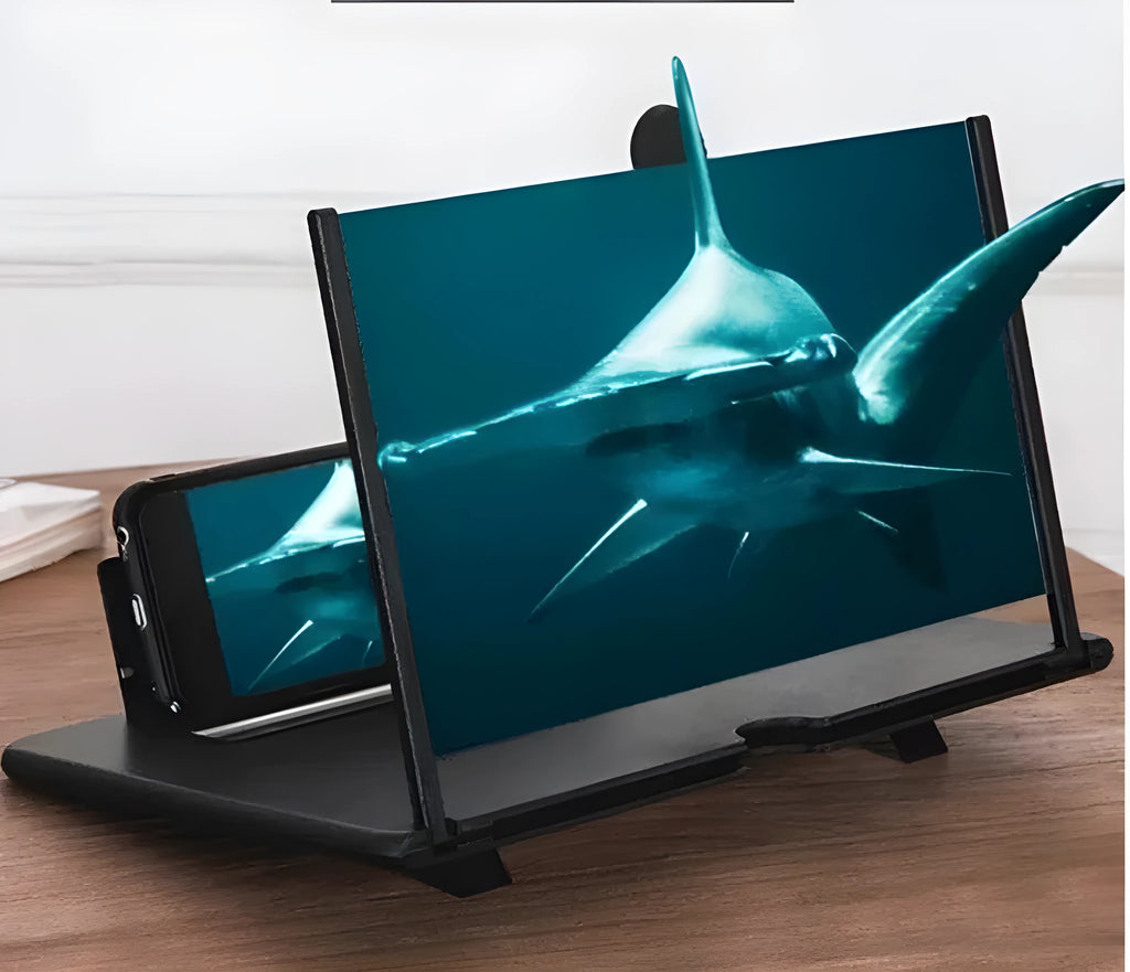Folding mobile phone screen amplifier in black, with phone inserted, showing 3-4x magnification on a desk