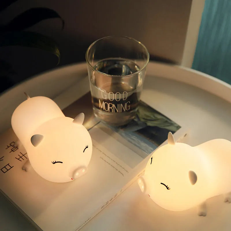 Dudu pig cartoon night light with silicone lampshade and warm yellow LED glow on a bedside table