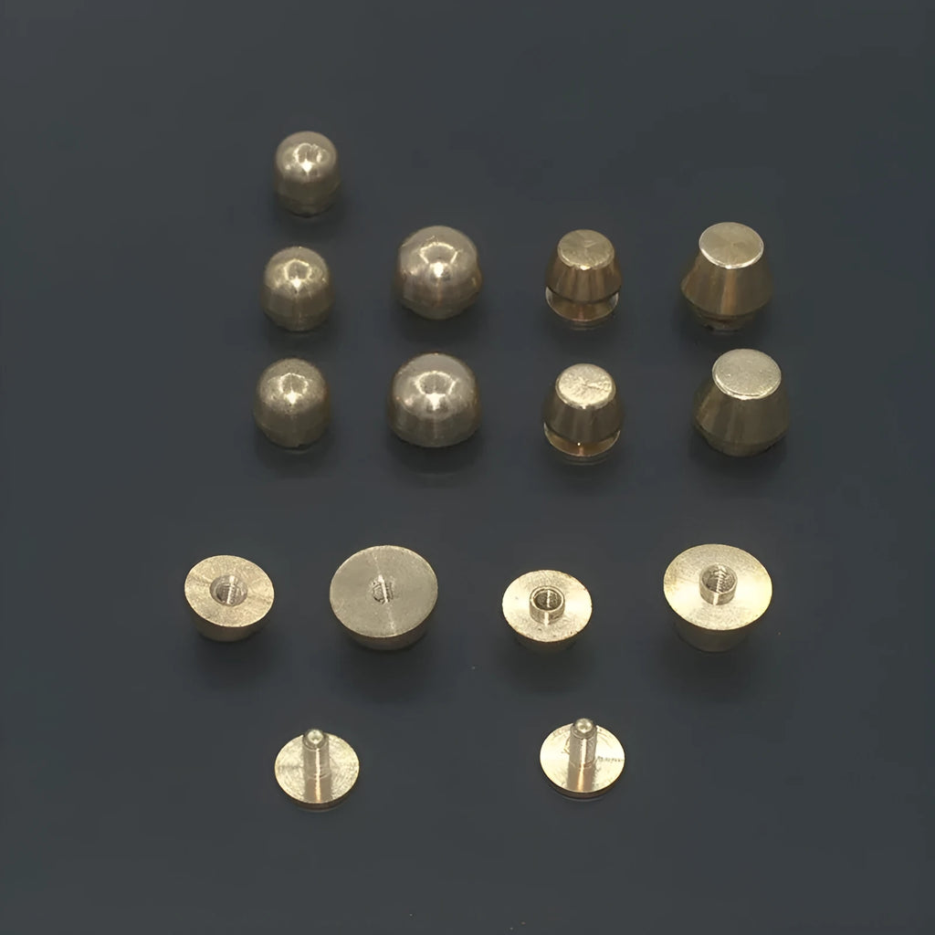 Brass decorative buckle with set of round and bucket-shaped brass foot nails on a surface.