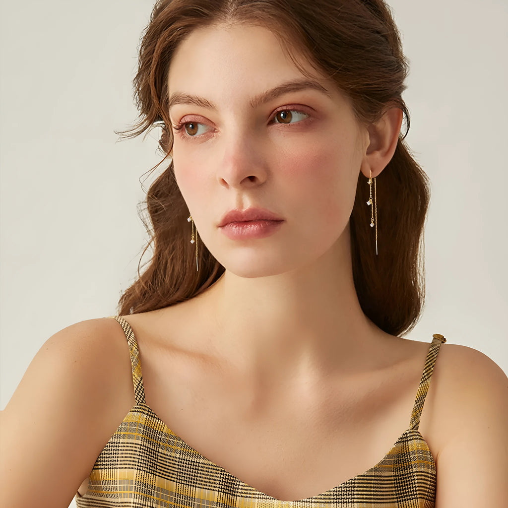 Gold pair of copper geometric round earrings with small zircon stone and ear hook closure on neutral background