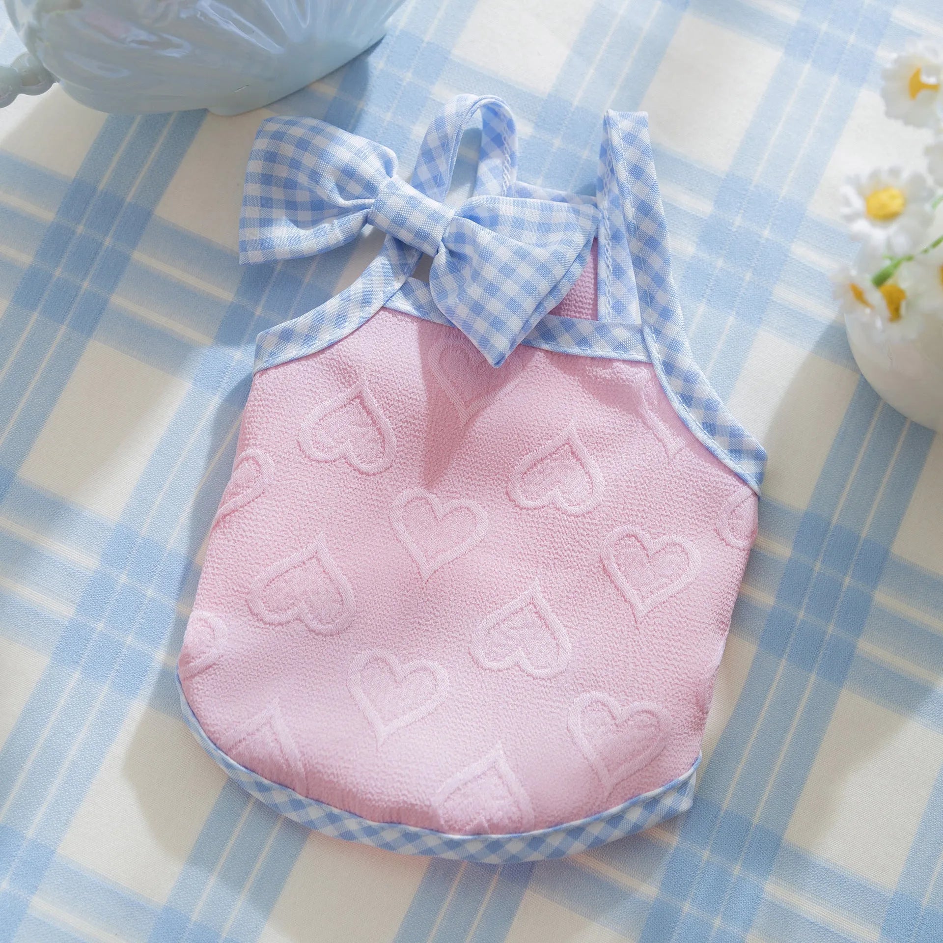 Small dog wearing a blue elastic vest with a heart texture and bow suspenders, with a matching hairband.
