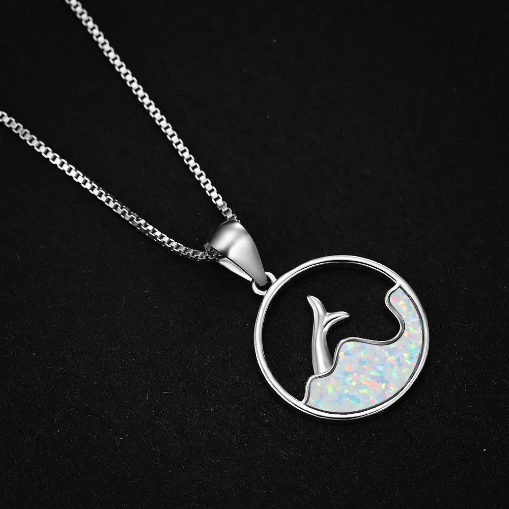 Close-up of a geometric pendant fishtail necklace with a round blue opal stone and white gold electroplated finish.