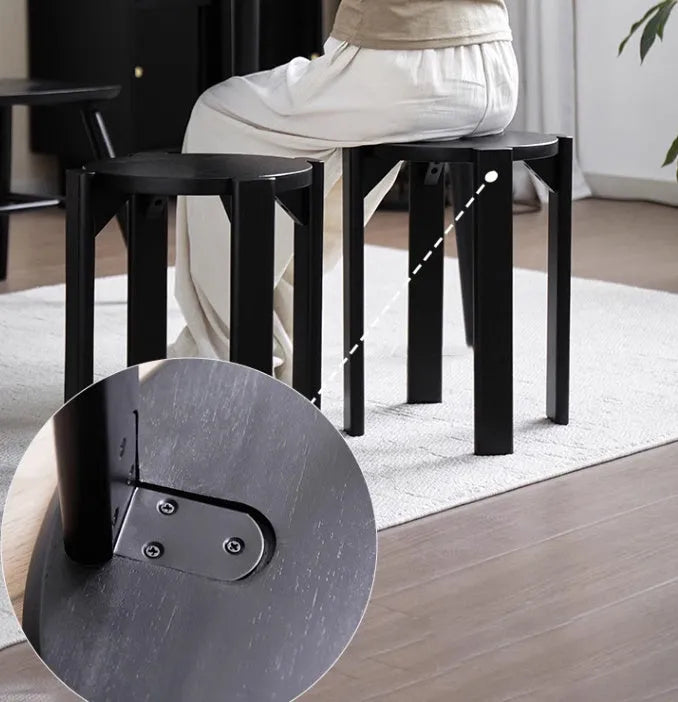 Set of four stackable iron dining stools with round seats in a modern design, shown in smoked black finish.
