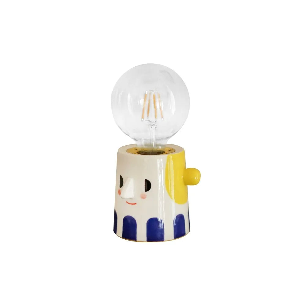 Off-white handmade ceramic table lamp with a rounded shape on a wooden surface.