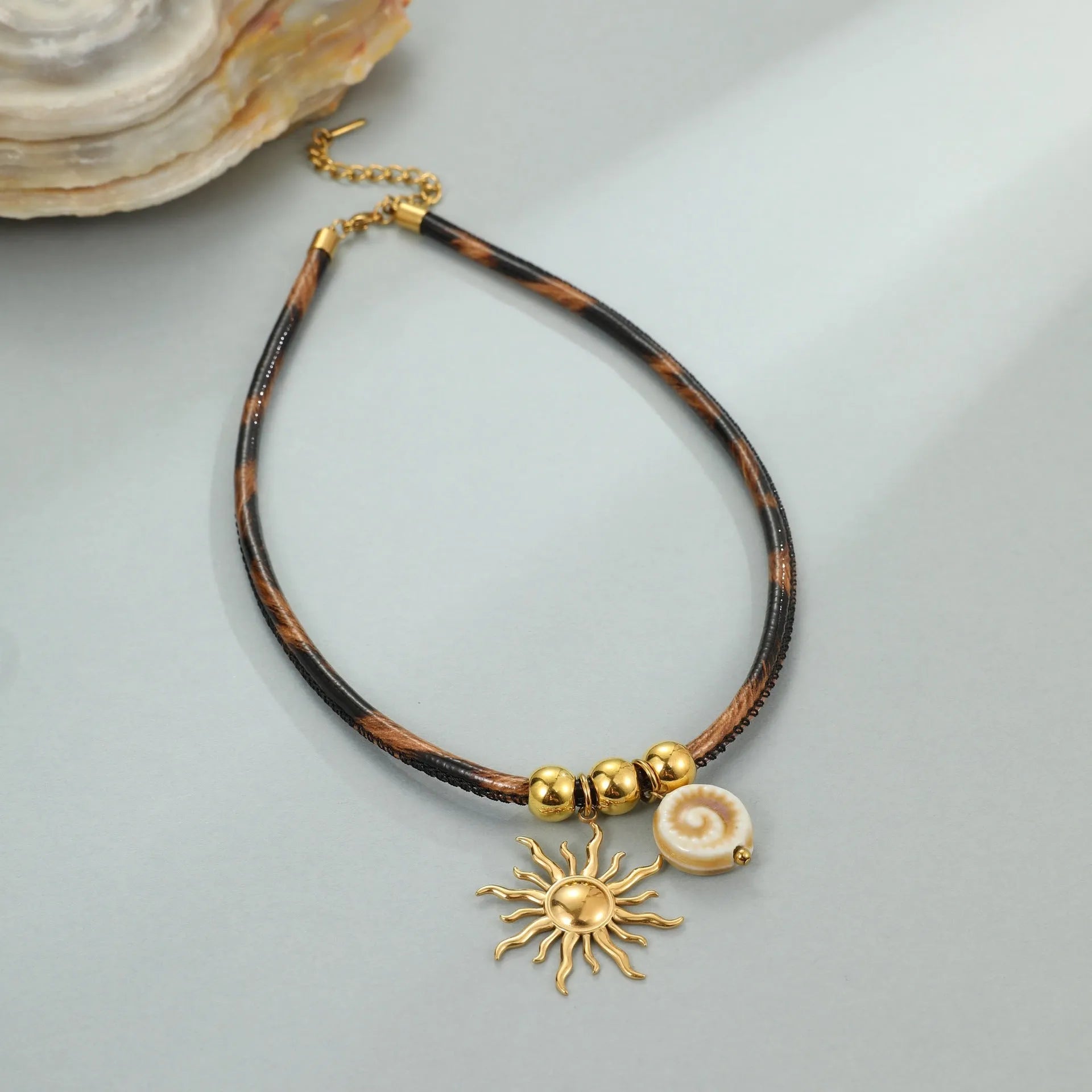 Geometric stainless steel necklace with leopard leather accents on pendant and gold-plated chain