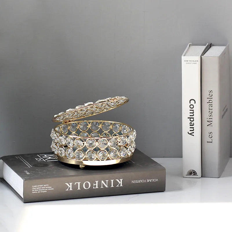 Transparent crystal glass jewelry storage box with a French gold-coloured metal frame on a table.