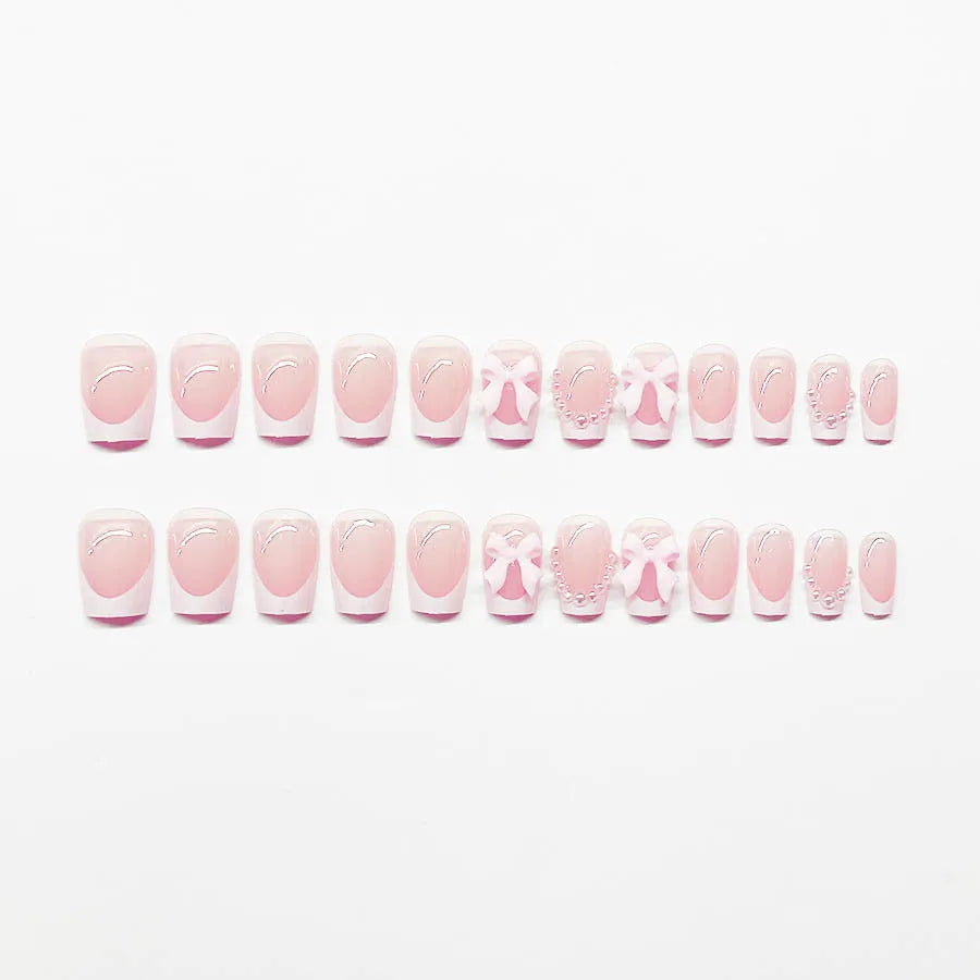 Set of 24 short, square, white-tipped French manicure false nails and a tube of nail glue on a pink background.