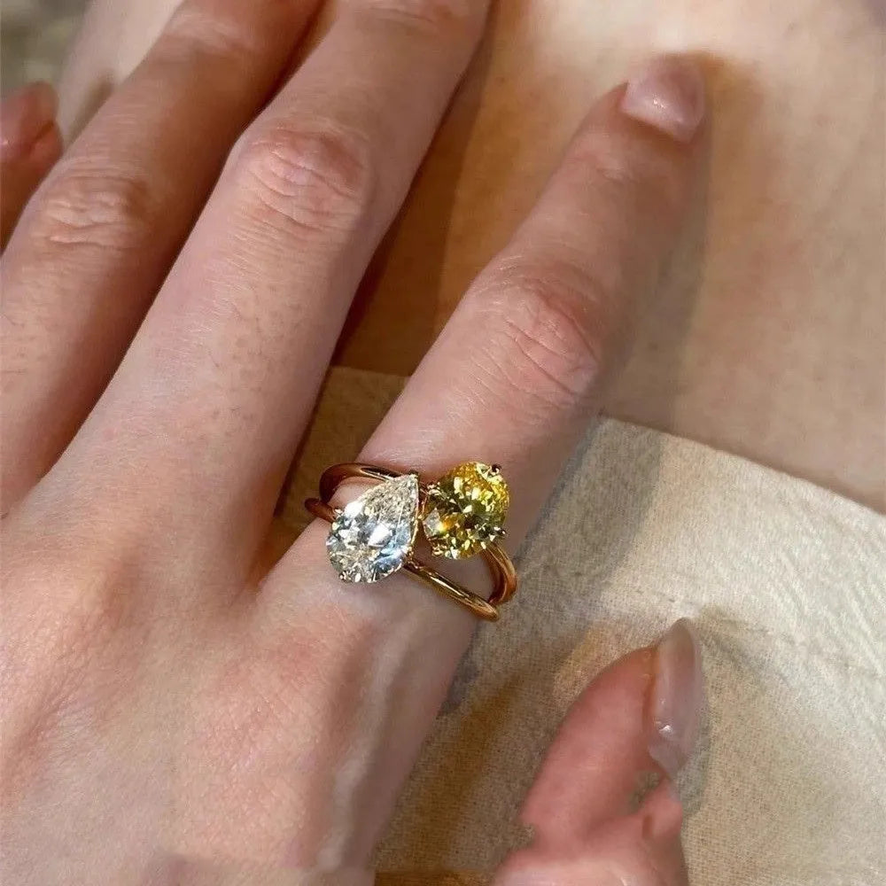 Geometric open copper ring with two sparkling zircon stones in a water drop setting on a model's finger.
