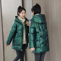 Women's loose-fit green hooded winter jacket with long sleeves on a hanger.