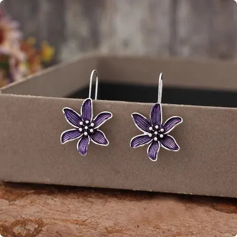 A pair of purple flower-shaped alloy earrings with an electroplated finish on a white background.