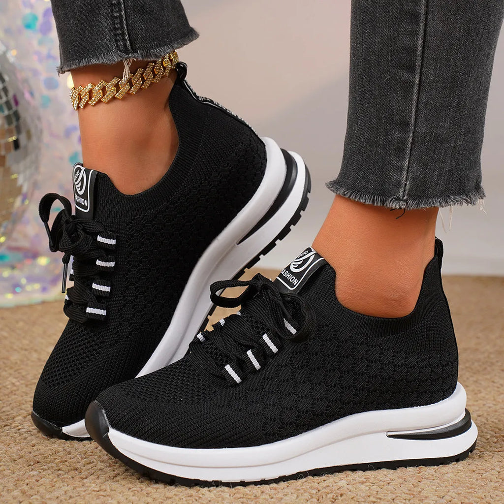 Women's black and white lace-up mesh platform sneakers with a flat rubber sole on a neutral background.