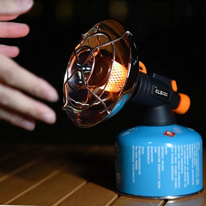 Black and orange mini portable camping stove with automatic ignition on a grassy outdoor surface.