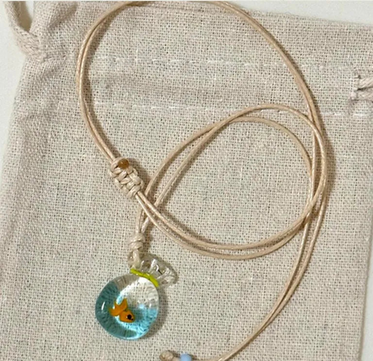 Women's coloured glaze pendant necklace on a braided cotton and linen clavicle chain, showing artisan finish.